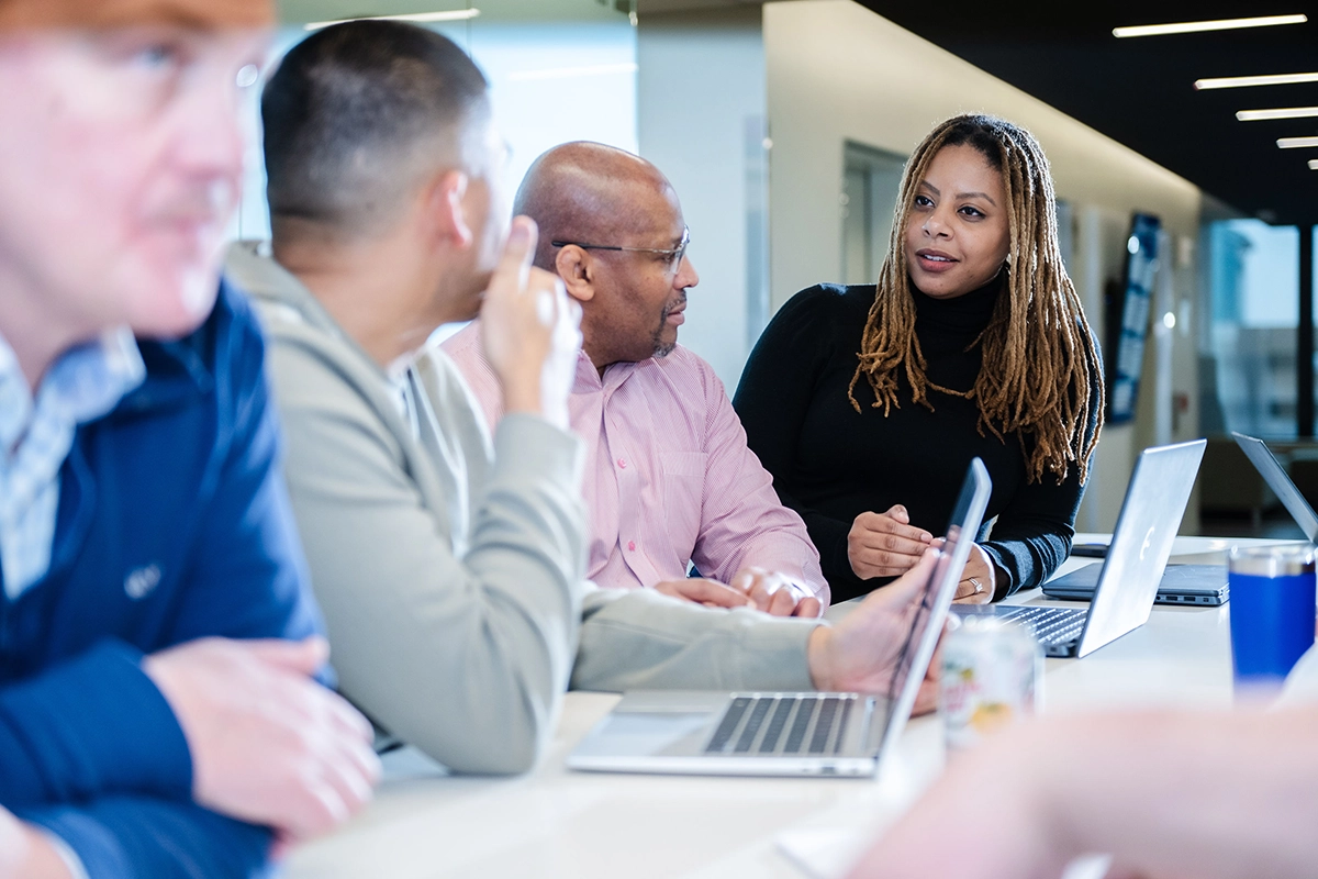 Diverse EMBA students having conversation standing in front of laptops.